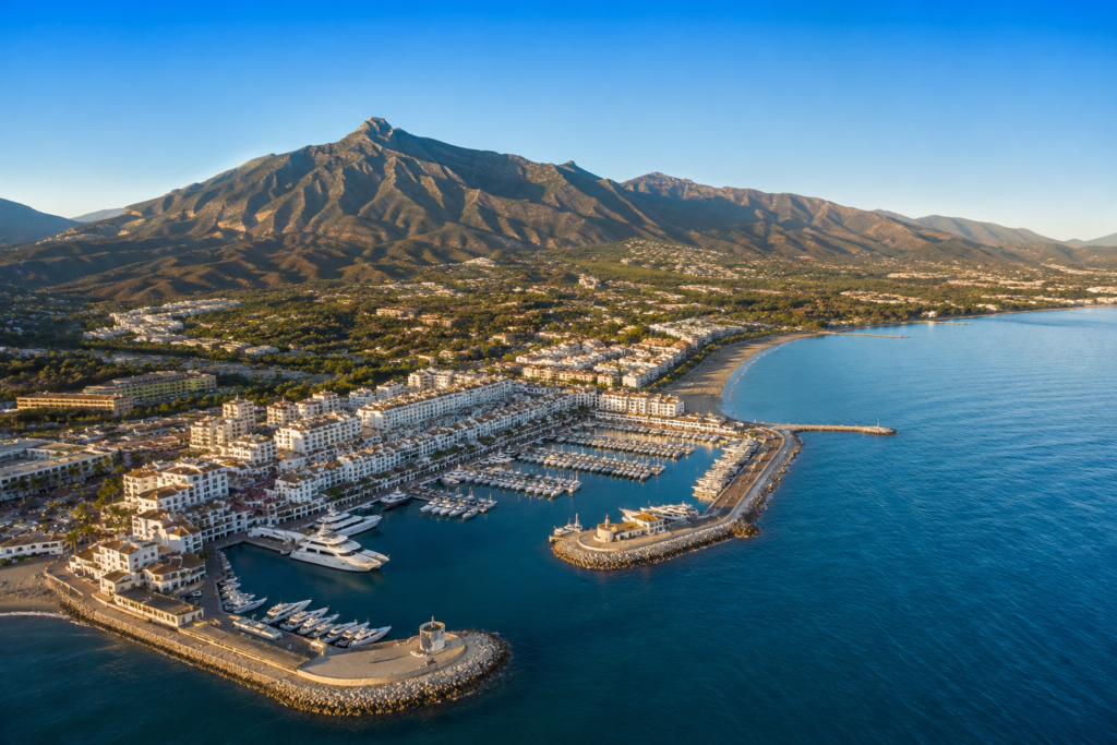Aerial view of Marbella showing luxury marina, Mediterranean coastline, beaches and the Sierra Blanca mountains.